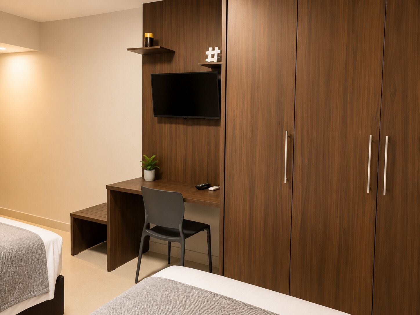 Una habitación de hotel con cama, escritorio, silla, televisor y armario.