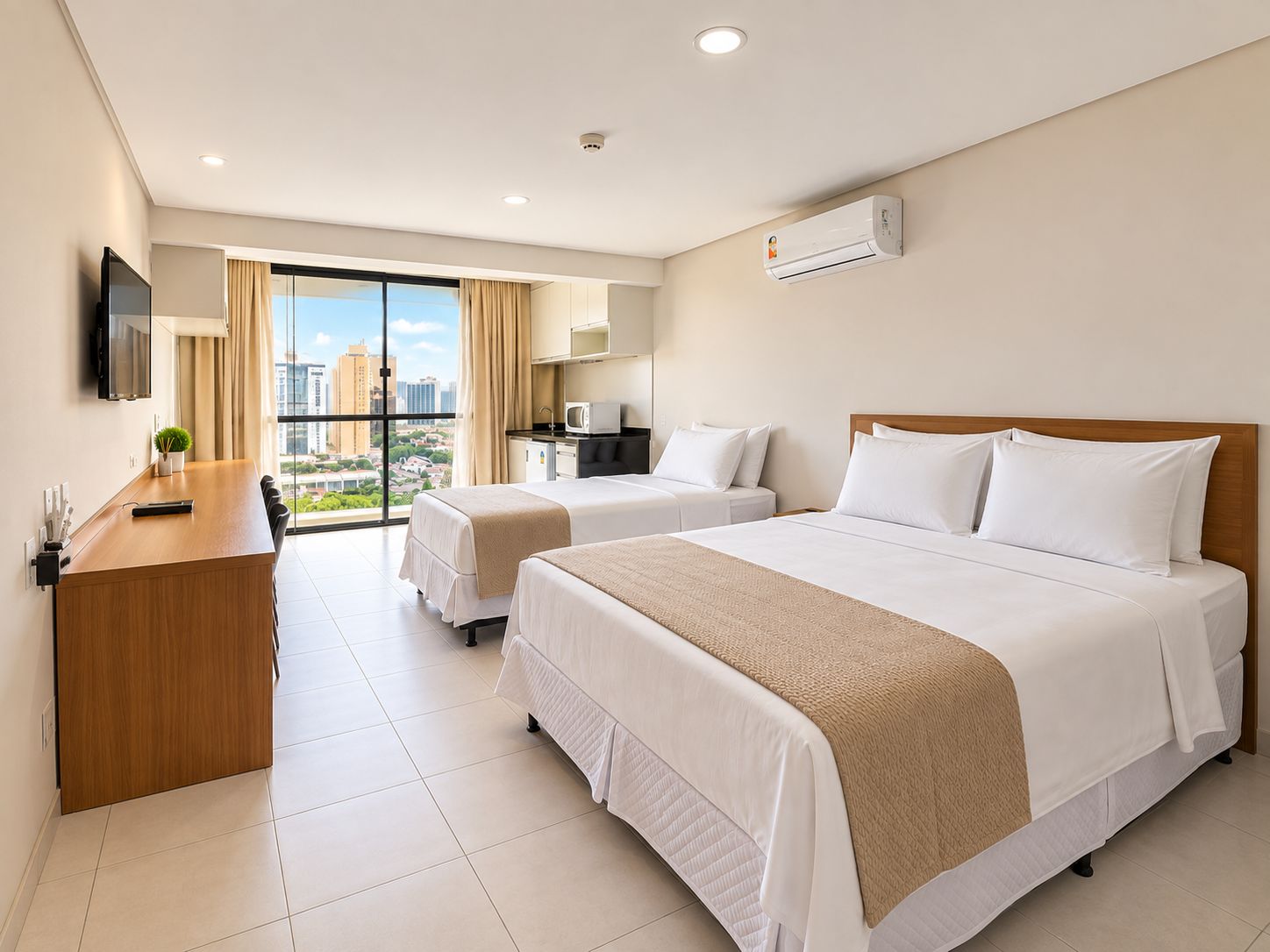 A hotel room with two beds, a desk, a TV, an air conditioner, and a view of the city.