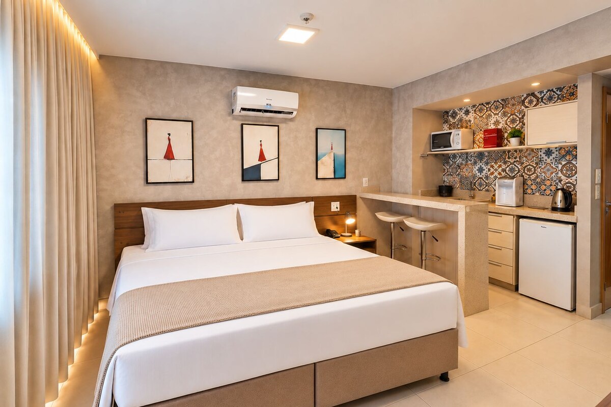 Una habitación de hotel con una cama, un escritorio, un microondas y una pequeña cocina.