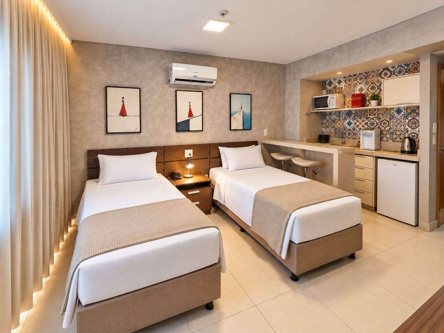 A hotel room with two beds, a kitchenette, and artwork on the walls.