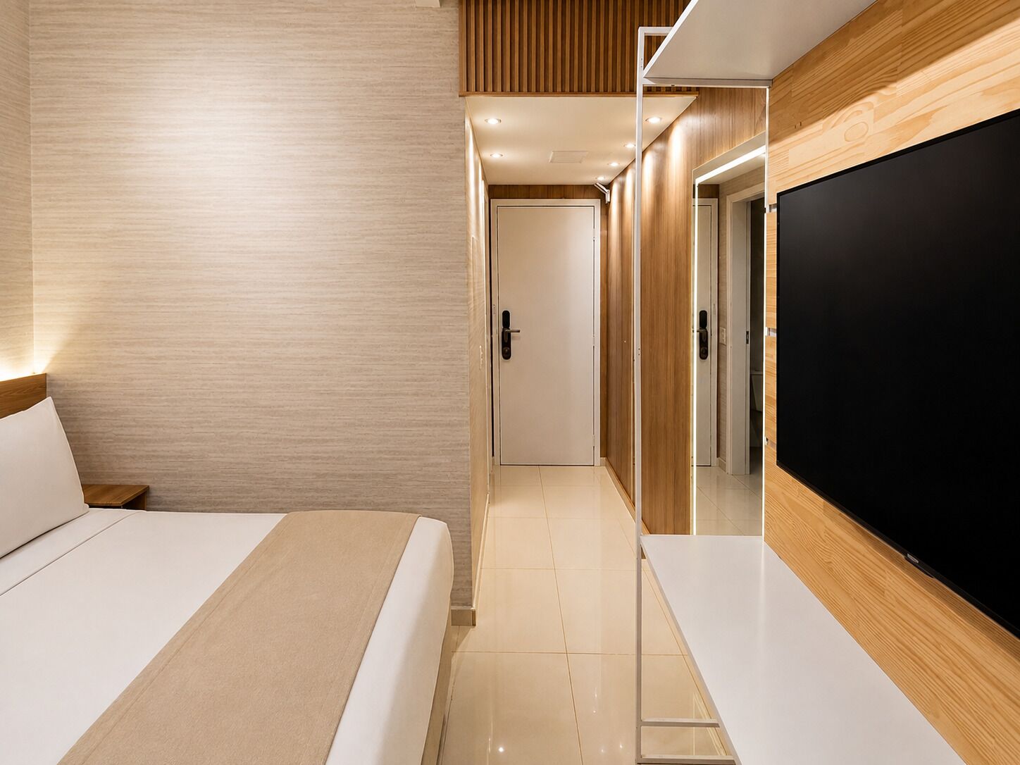 Une chambre d’hôtel moderne équipée d’un lit, d’un téléviseur à écran plat et d’un mur recouvert de panneaux en bois.