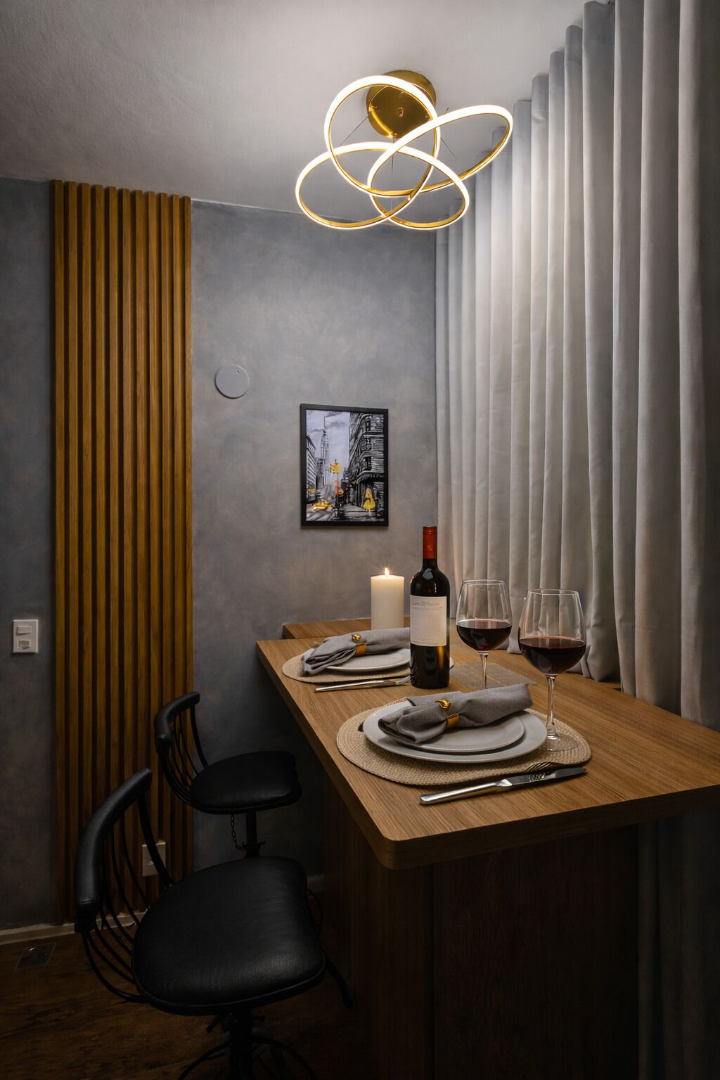Comedor con una mesa de madera dispuesta para dos personas, una vela, una botella de vino y copas.