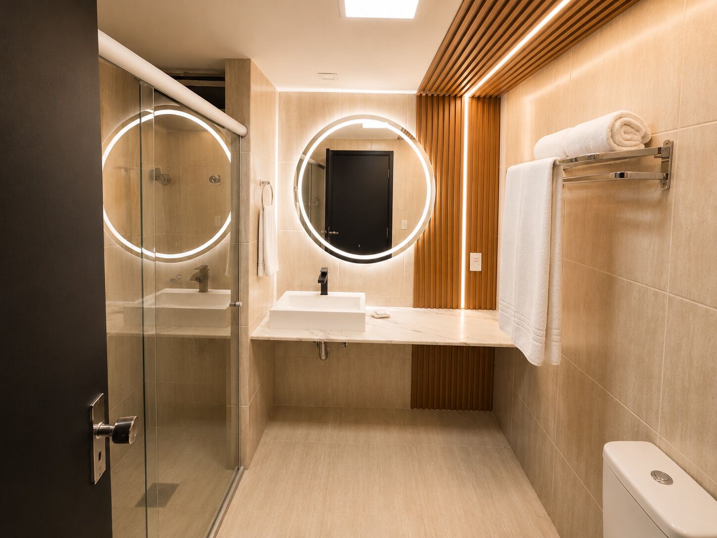 A modern bathroom with a glass shower enclosure, a vanity with a mirror, and a toilet.