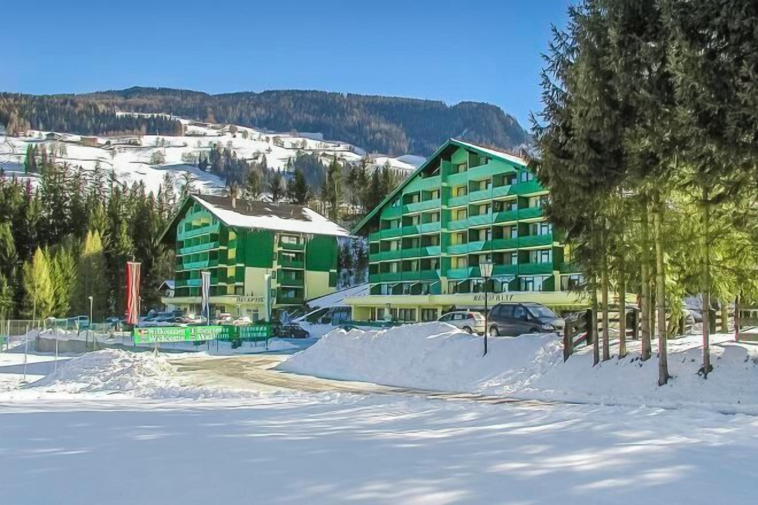 A hotel with multiple floors, surrounded by snow-covered landscape and mountains in the background.