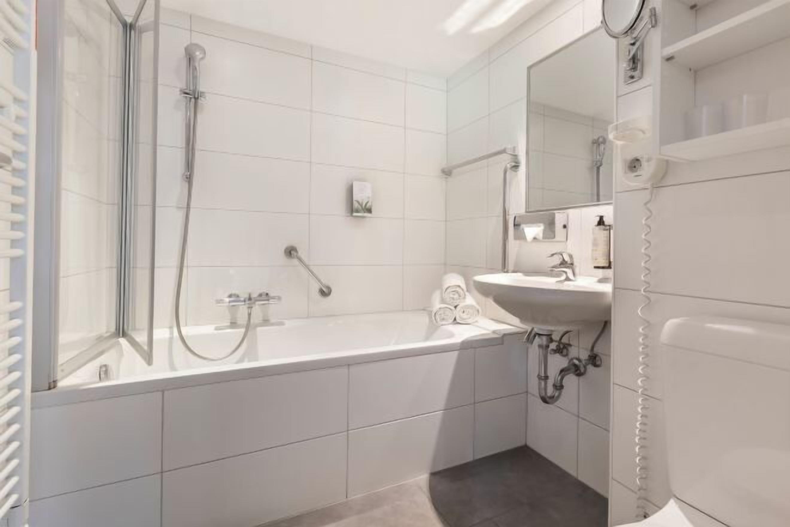 A modern bathroom with a bathtub, a shower, a sink, and a mirror.