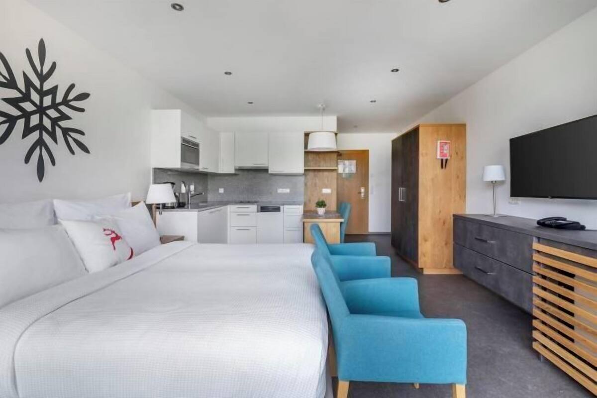 A modern hotel room with a bed, a desk, and a TV.