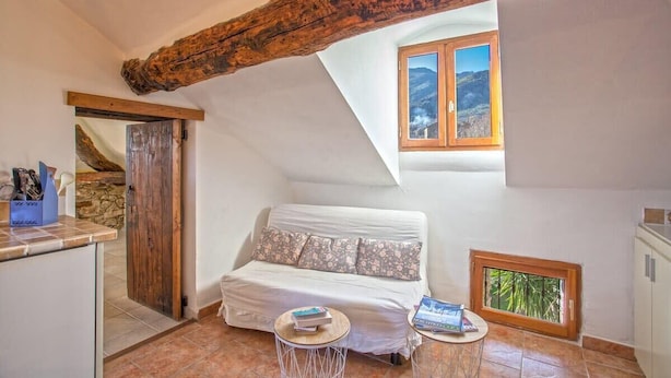 Une pièce confortable avec un lit, une petite table, une fenêtre donnant sur un beau paysage et une poutre rustique au plafond.