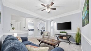A living room with a sofa, coffee table, and a TV mounted on the wall.