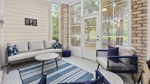A sunroom with a sofa, chairs, and a small table.