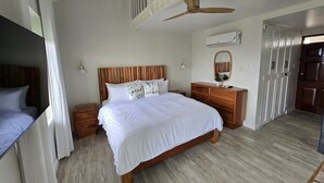 A bedroom with a wooden bed, a ceiling fan, a bedside table, a dresser, and a wardrobe.