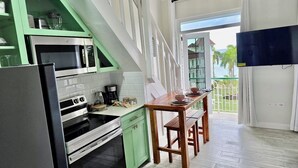 A kitchen with green cabinets, a wooden table, and a view of the outside.