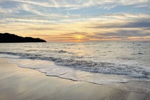 Ein Strand bei Sonnenuntergang mit Wellen.