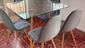 A glass-top dining table with four grey upholstered chairs with wooden legs. - HOUSE IN LO DE MARCOS, NAYARIT - UP TO 8 PEOPLE AND PETS (Lo de Marcos)