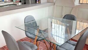 A glass-top dining table with four grey upholstered chairs, set in a room with a tiled floor and a white wall. - HOUSE IN LO DE MARCOS, NAYARIT - UP TO 8 PEOPLE AND PETS (Lo de Marcos)