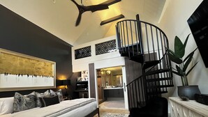 A modern bedroom with a bed, a black spiral staircase, a large mirror, and a view into the kitchen. - IF Stay Collection is an exquisite and unexpected stand alone Row House. (Carriere)