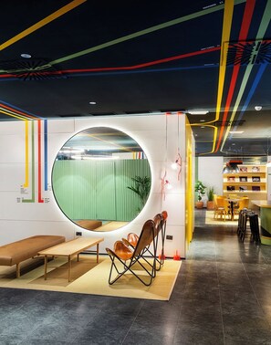 A modern interior with a circular window, seating area, and a bookshelf. - B&B Hotel Castellón (Castelló de la Plana)