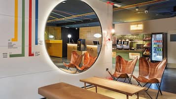 Een modern interieur met een ronde spiegel, een zithoek en een toonbank met neonreclame.