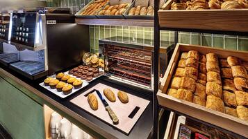 Una vetrina di pasticceria con dolci, una macchina da caffè e un forno per il pane.
