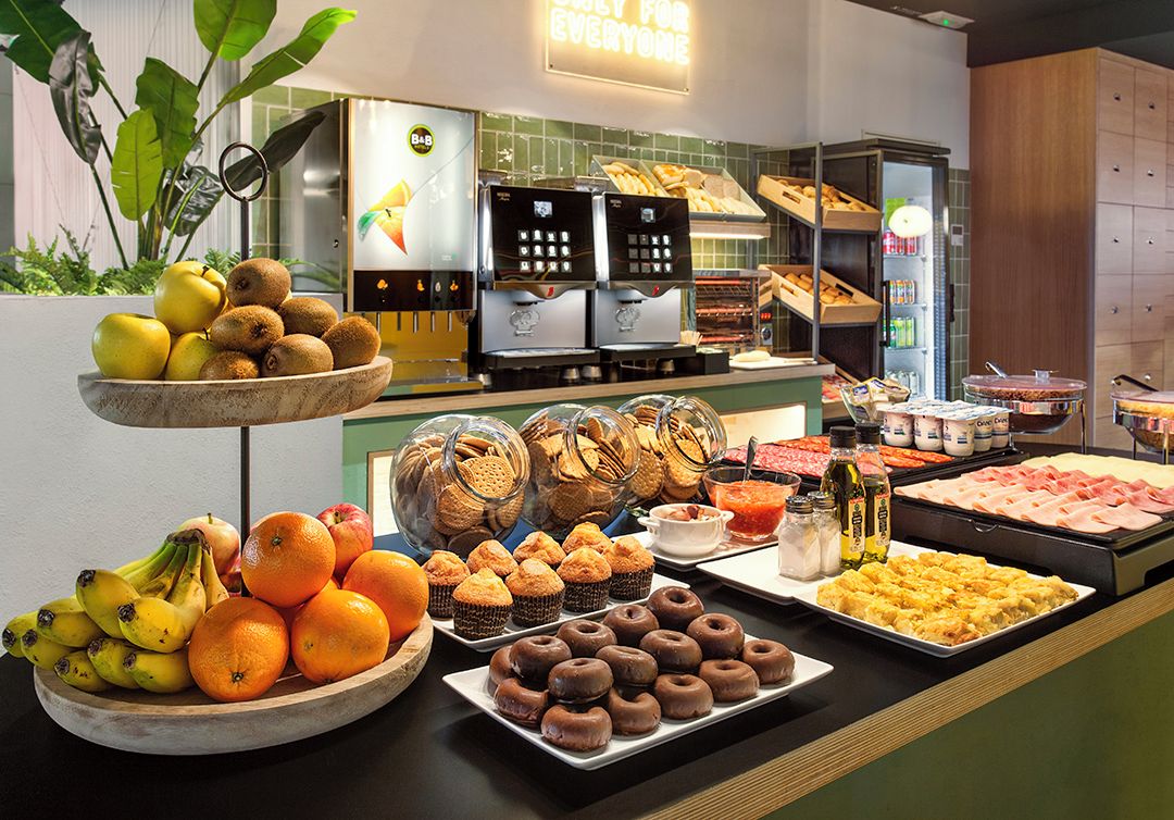 A buffet with various food items, including fruits, pastries, and a coffee station.