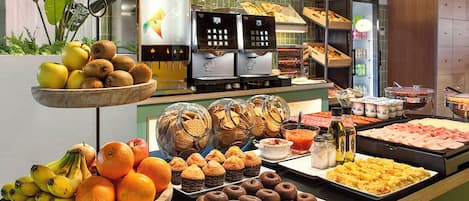 A buffet with various food items, including fruits, pastries, and a coffee station.