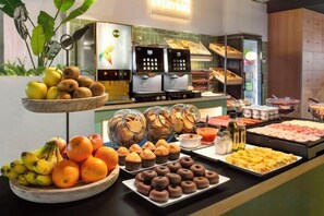Un bufé con diferentes opciones de comida, incluyendo frutas, pasteles y postres.