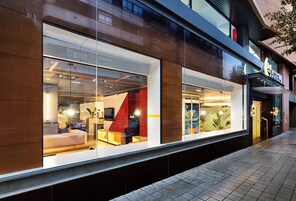 Interior moderno de hotel con ventanas amplias, una zona de estar visible y una entrada a la vista.