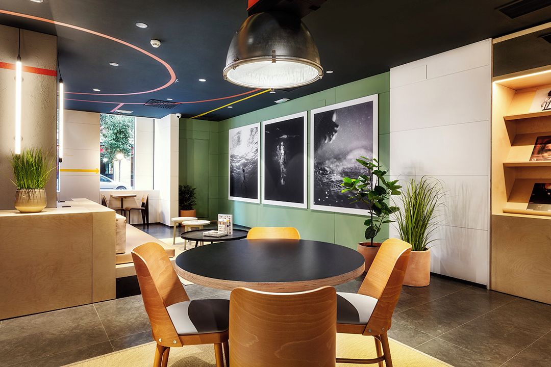 A modern interior with a round table, chairs, potted plants, and wall art.