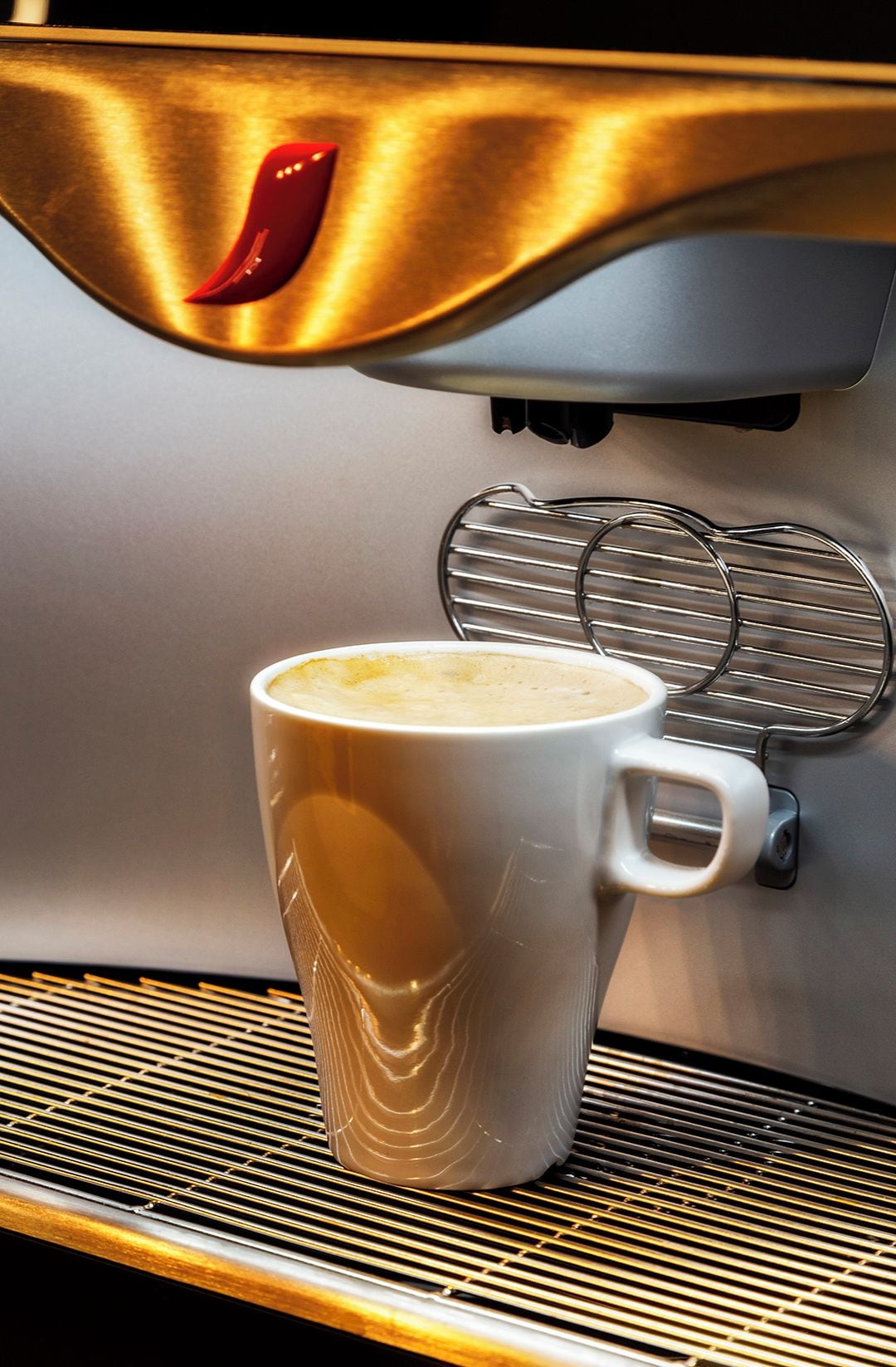 A coffee machine dispensing coffee into a white mug.