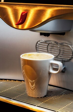 A coffee machine dispensing coffee into a white mug. - B&B Hotel Castellón (Castelló de la Plana)