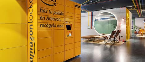 A yellow Amazon Locker with a digital interface, a bench, and a circular window in a modern interior.
