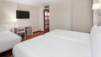 Una habitación de hotel con dos camas, un escritorio, una silla, un televisor y una puerta.