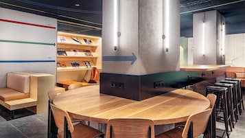 Un intérieur moderne avec une table et des chaises en bois, un canapé et un coin bar avec des tabourets.
