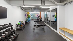 A gym with exercise equipment, a bench, and a wall-mounted TV. - King Bed, Gym, 2min walk to UAB, Foodie Haven (Birmingham)