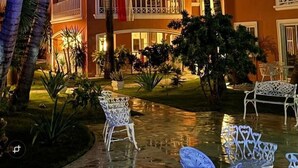 Ein mehrstöckiges Hotel mit Balkonen, Palmen und Sitzgelegenheiten im Freien.
