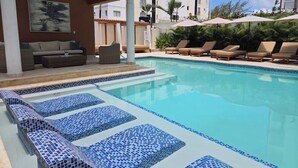 Ein Pool mit Liegestühlen und einer überdachten Sitzgruppe.