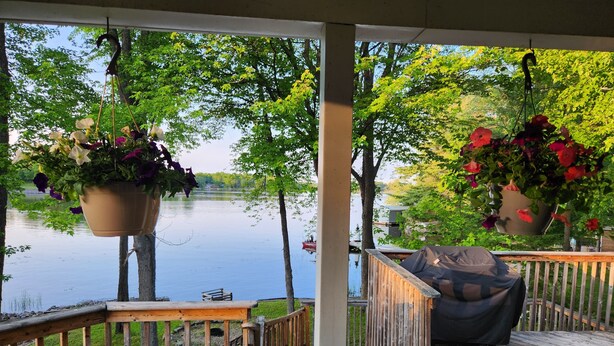 Une terrasse en bois agrémentée de jardinières suspendues, donnant sur un lac paisible.