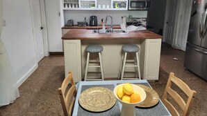 Une cuisine compacte dotée d’un îlot central, de meubles blancs, d’un four à micro-ondes et d’un réfrigérateur.