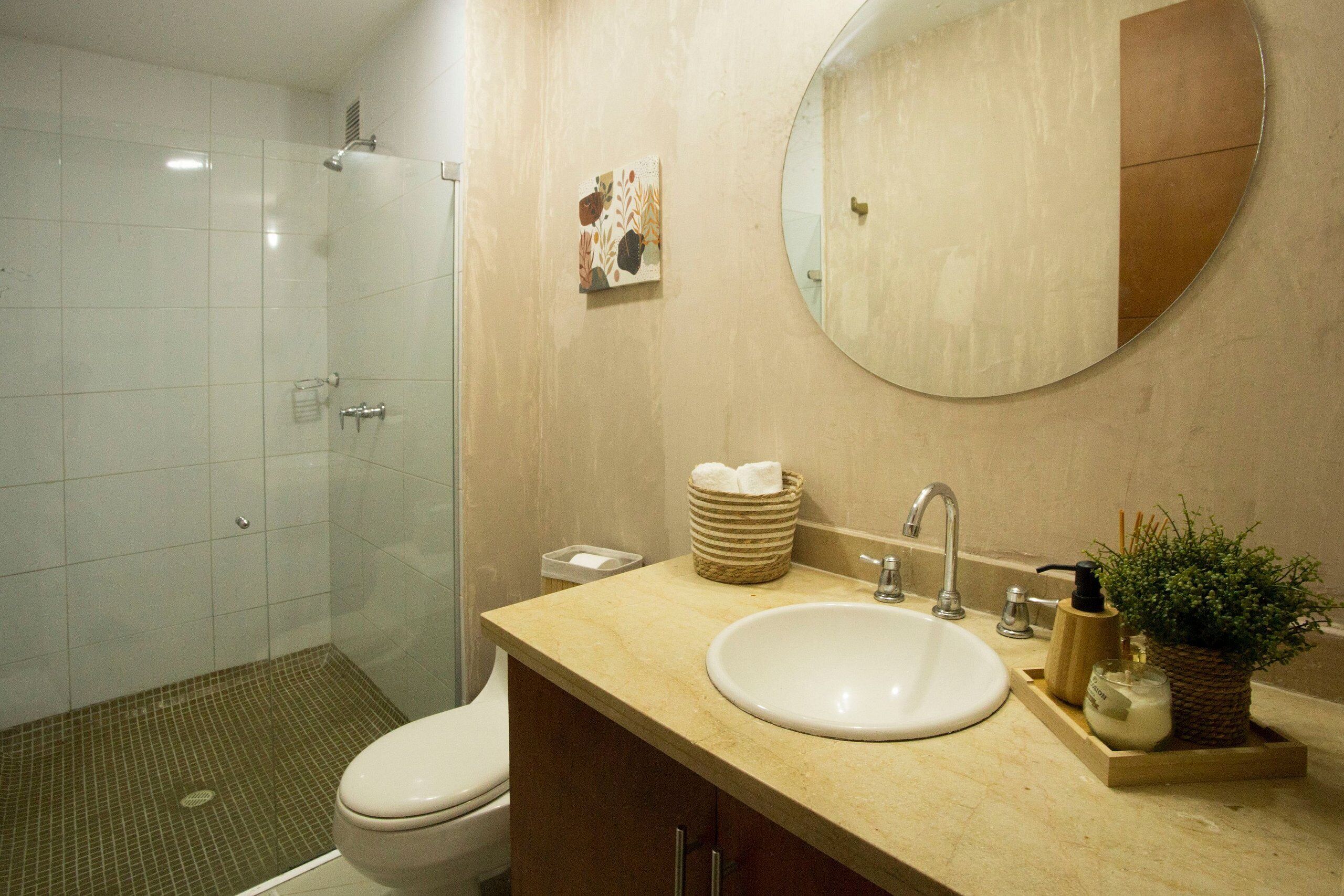 A bathroom with a toilet, sink, and shower.