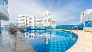 A rooftop swimming pool with a checkered pattern, surrounded by a blue fence and a view of high-rise buildings. - Poseidon del Caribe (Cartagena)