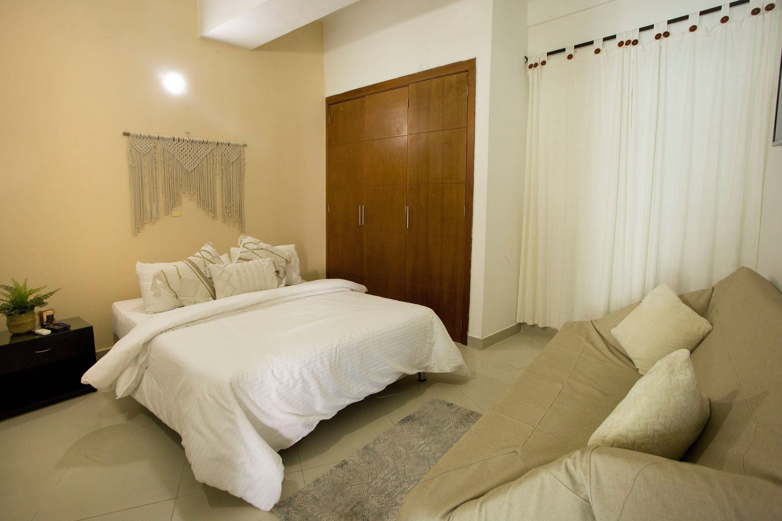 Un dormitorio con cama, sofá, armario y cortina.
