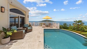 A pool area with wicker furniture and a view of the ocean. - Generator! 2 Primary Bedrooms - Magens Bay - Dining (St. Thomas)