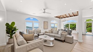 A spacious living room with a large sofa, armchairs, and a coffee table. There are multiple windows offering views of the outdoors. - Generator! 2 Primary Bedrooms - Magens Bay - Dining (St. Thomas)