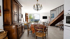 Eine geräumige Küche mit Essbereich, Holzschränken, einem Chandelier und einer Treppe, die zu einer weiteren Ebene führt.