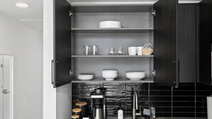 Een moderne keuken met zwarte kasten, een koffiezetapparaat en een spoelbak.