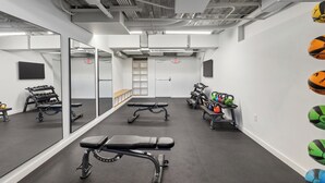 Een sportschool met trainingsapparatuur, een bank en een muur met fitnessballen.