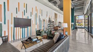 Een moderne woonkamer met een grote flatscreen televisie, comfortabele zithoek en een decoratieve wand met abstracte patronen.