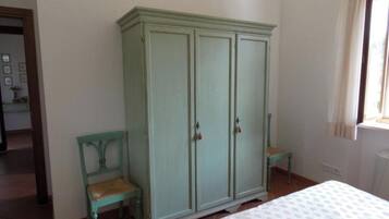 A bedroom with a bed, a green wardrobe, and a chair.