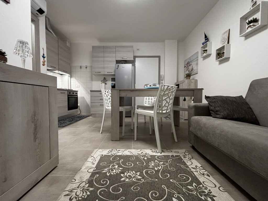 Een ruimtelijk ingerichte leefruimte met kitchenette, eethoek en een bank.
