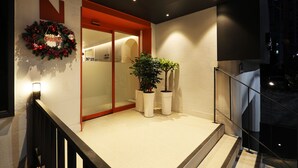 Entrada d'un hotel amb una porta vermella, una corona de Nadal i plantes en testos.