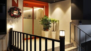 Entrada d'hotel amb una corona de Nadal, un rètol del Hotel número 25 i una escala amb barana.